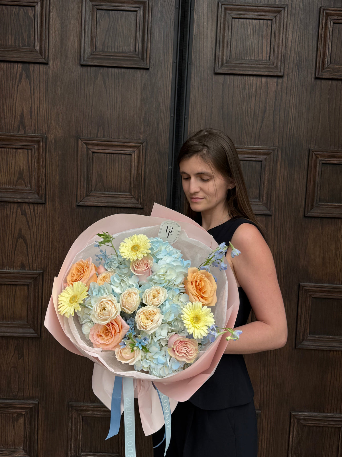 Garden-inspired pink and peach bouquet wrapped in blue paper