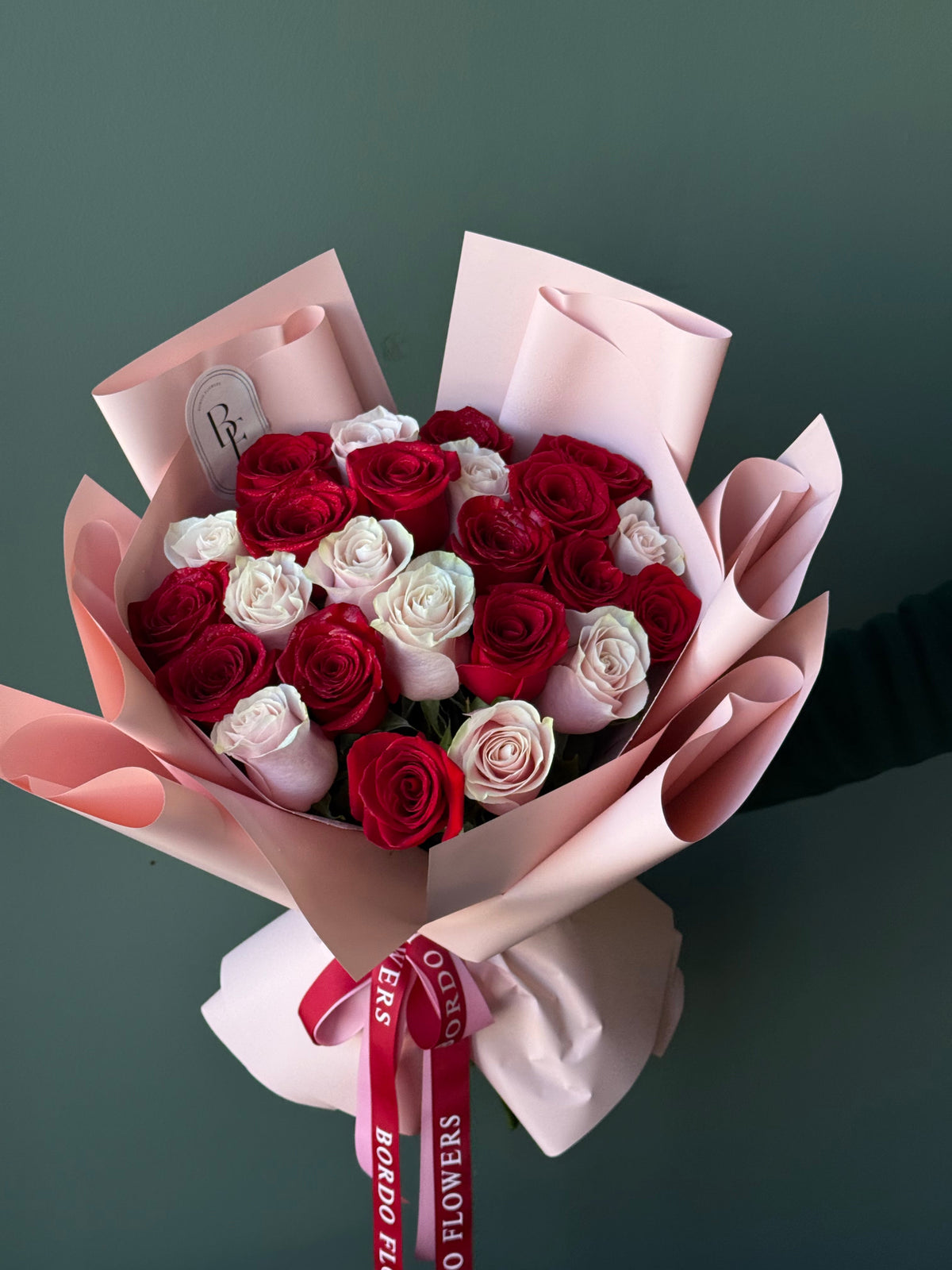 24 colorful roses wrapped in elegant paper with signature ribbon