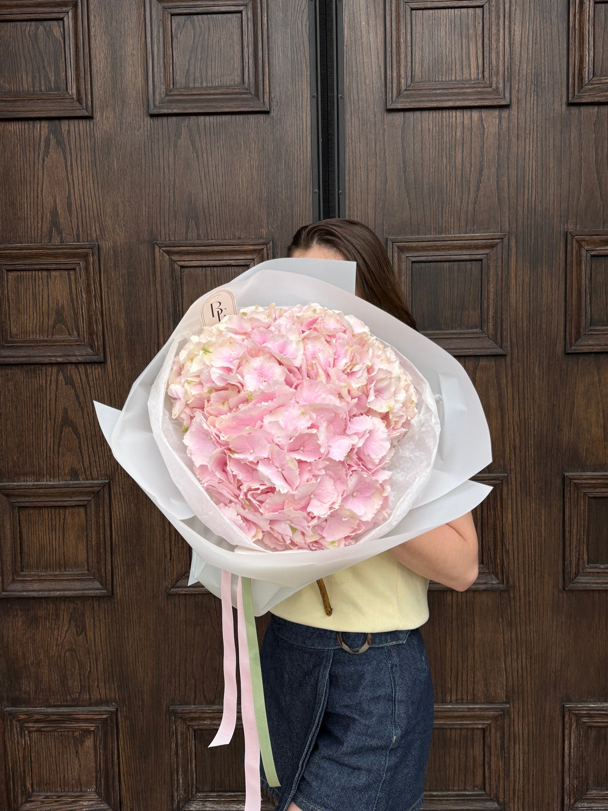Round hydrangea bouquet wrapped in soft pink paper