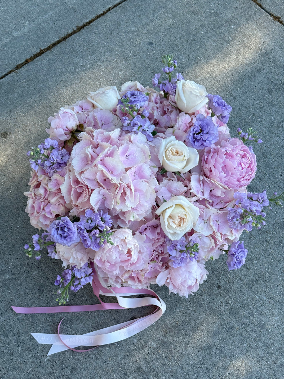 Pink and lavender Sole Mio floral arrangement in a woven basket